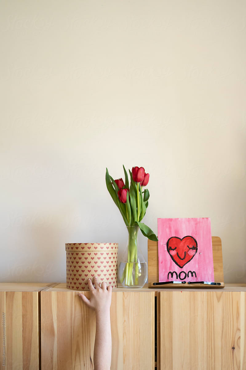 Hand holding vase on cabinet with gifts for mothers day