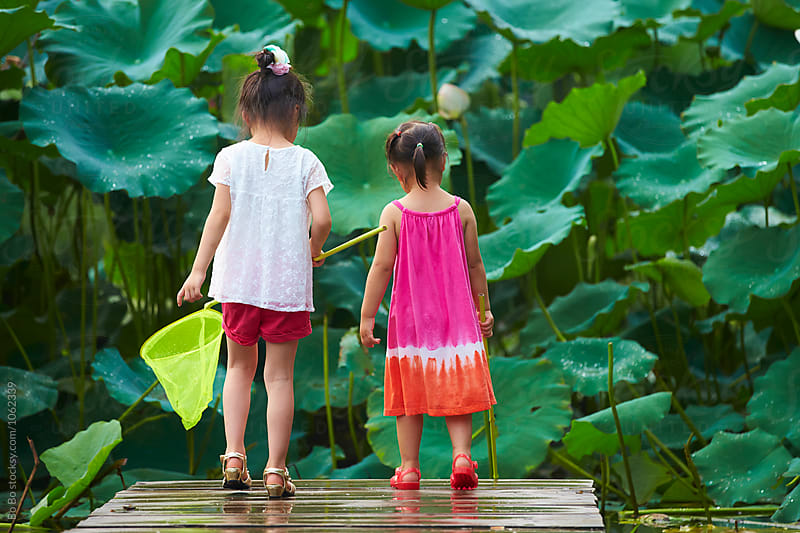 two little girls holding net by the pond side