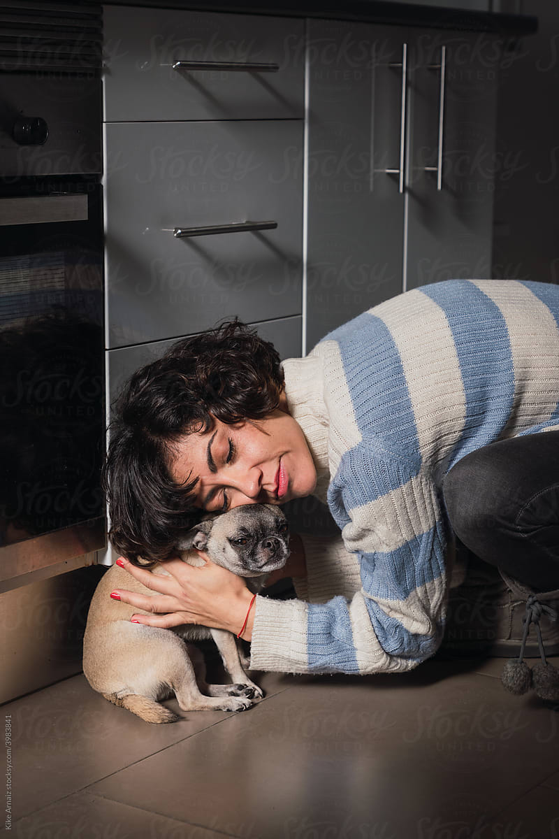 Stylish woman hugging dog at home