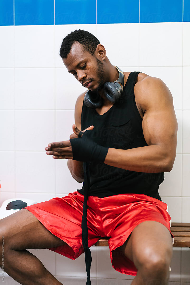 Brutal black sportsman wrapping hands in changing room