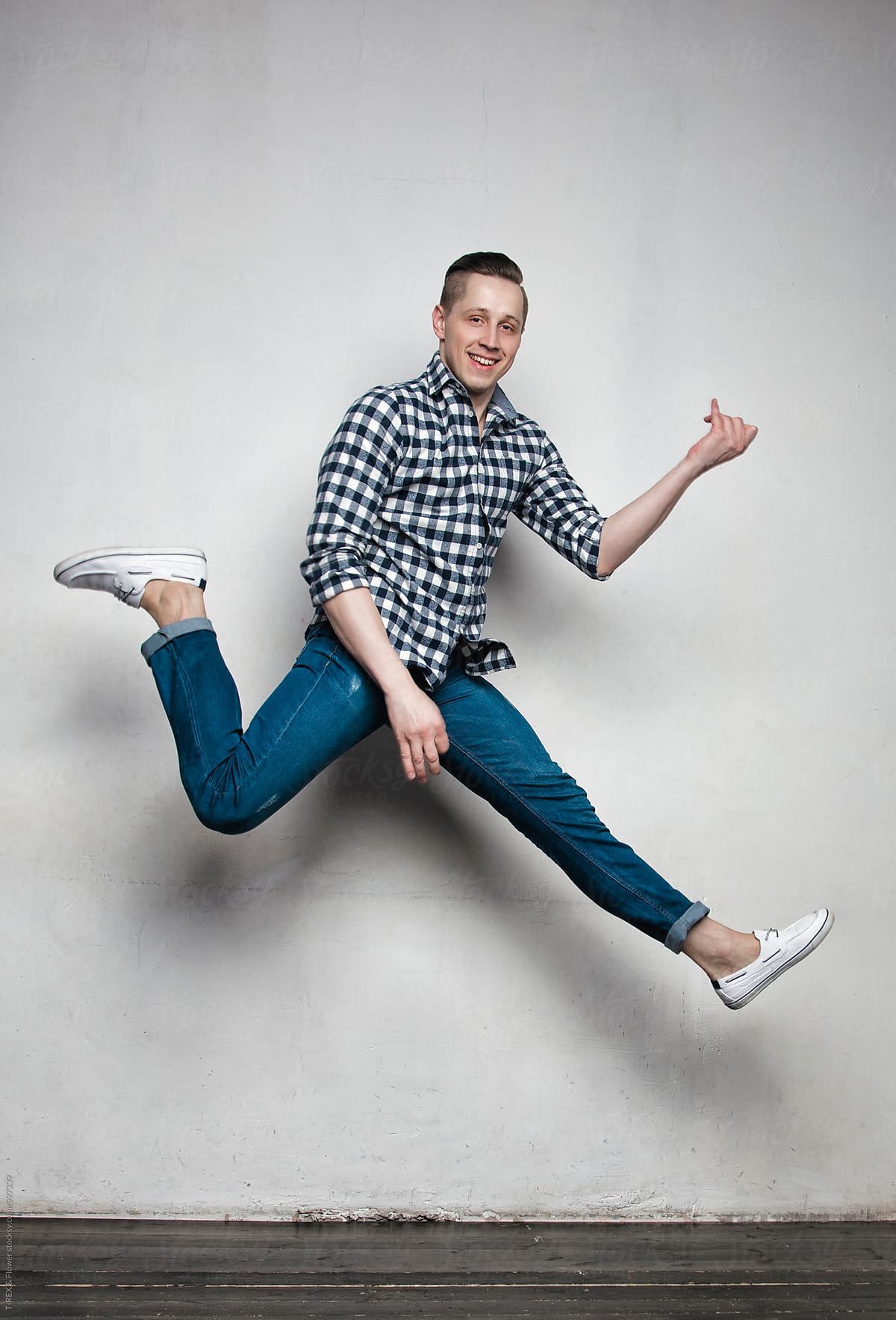 Smiling young male in plaid shirt leaping