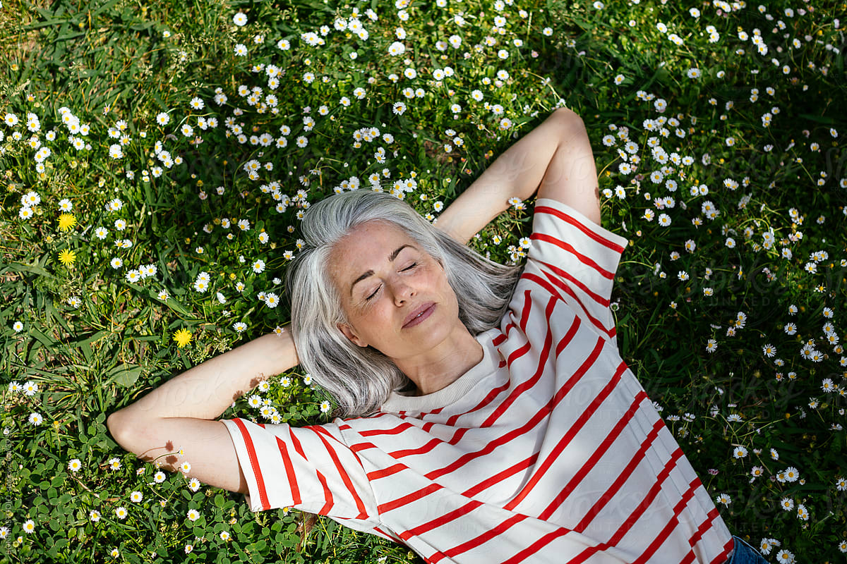 Calm mature woman relaxing on lawn