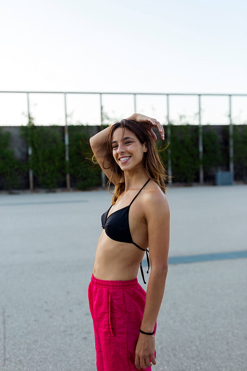 Young happy sporty woman smiling at camera outdoors