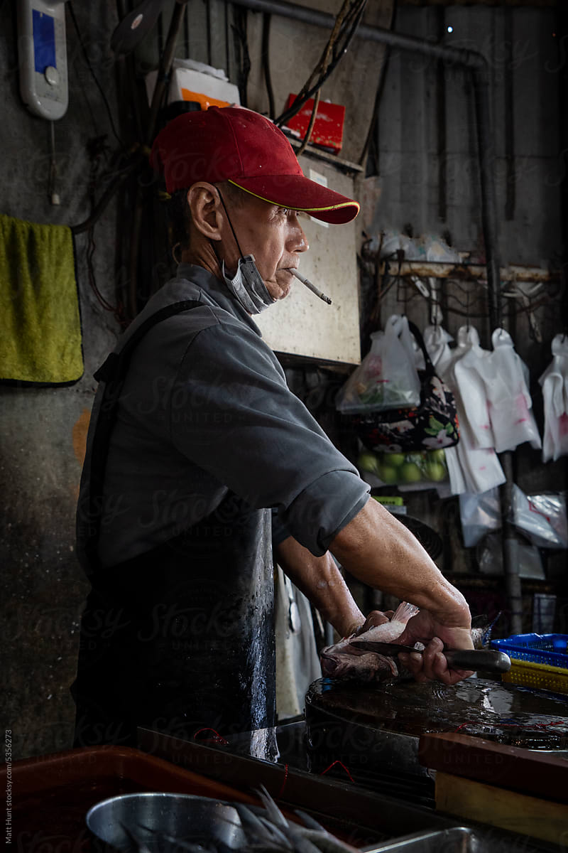 Smoking a cigarette while chopping fish for sale at amarket in Taiwan