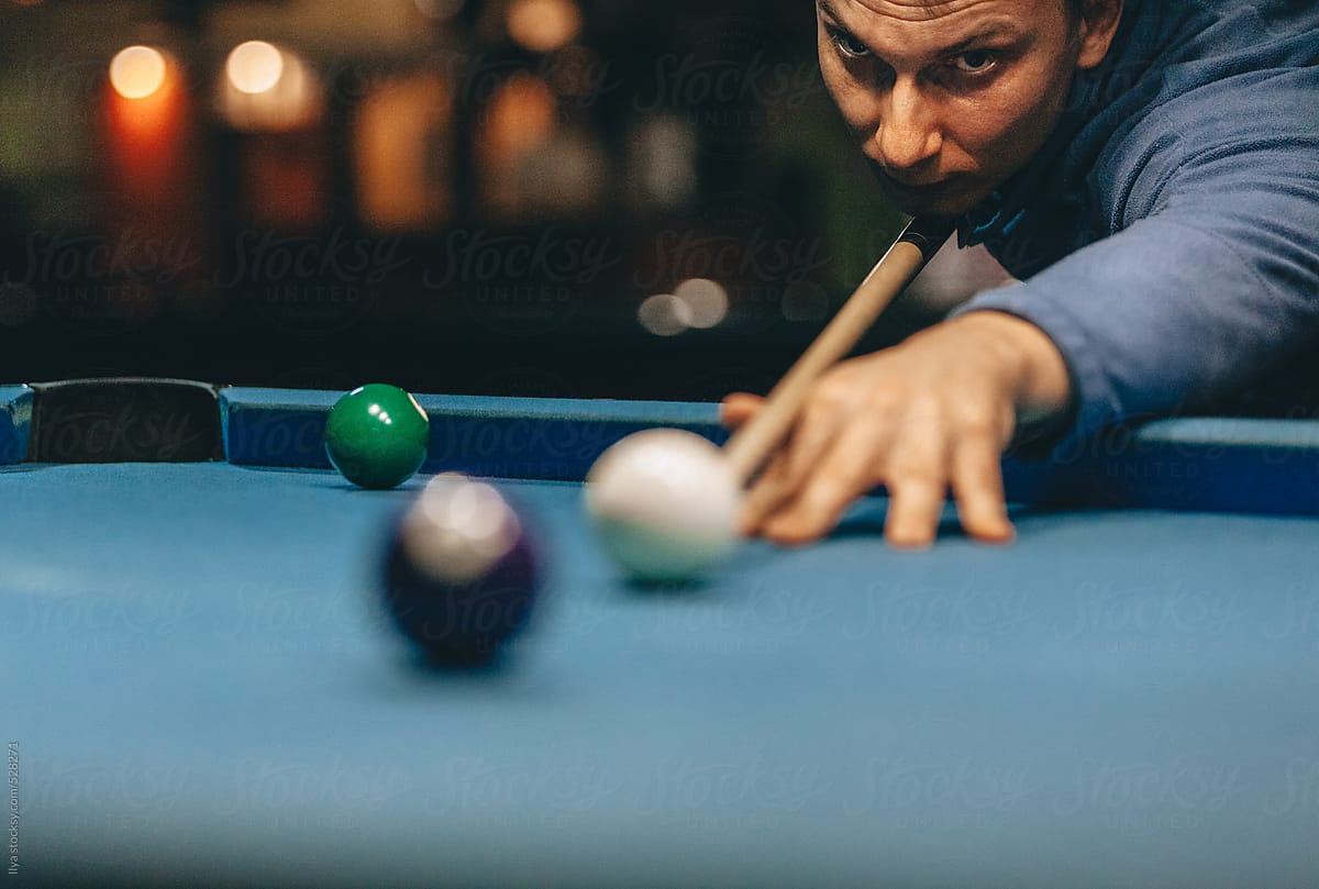 Man taking a shot in pool billiard game in night club