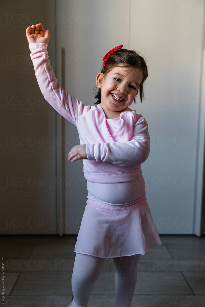 Happy child in pink dress dancing at home