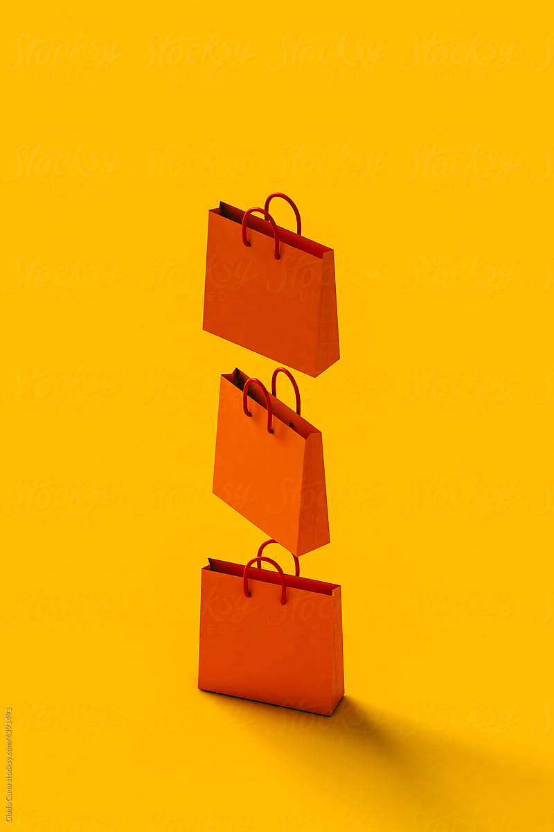 vertical row of Orange shopping bag on yellow.