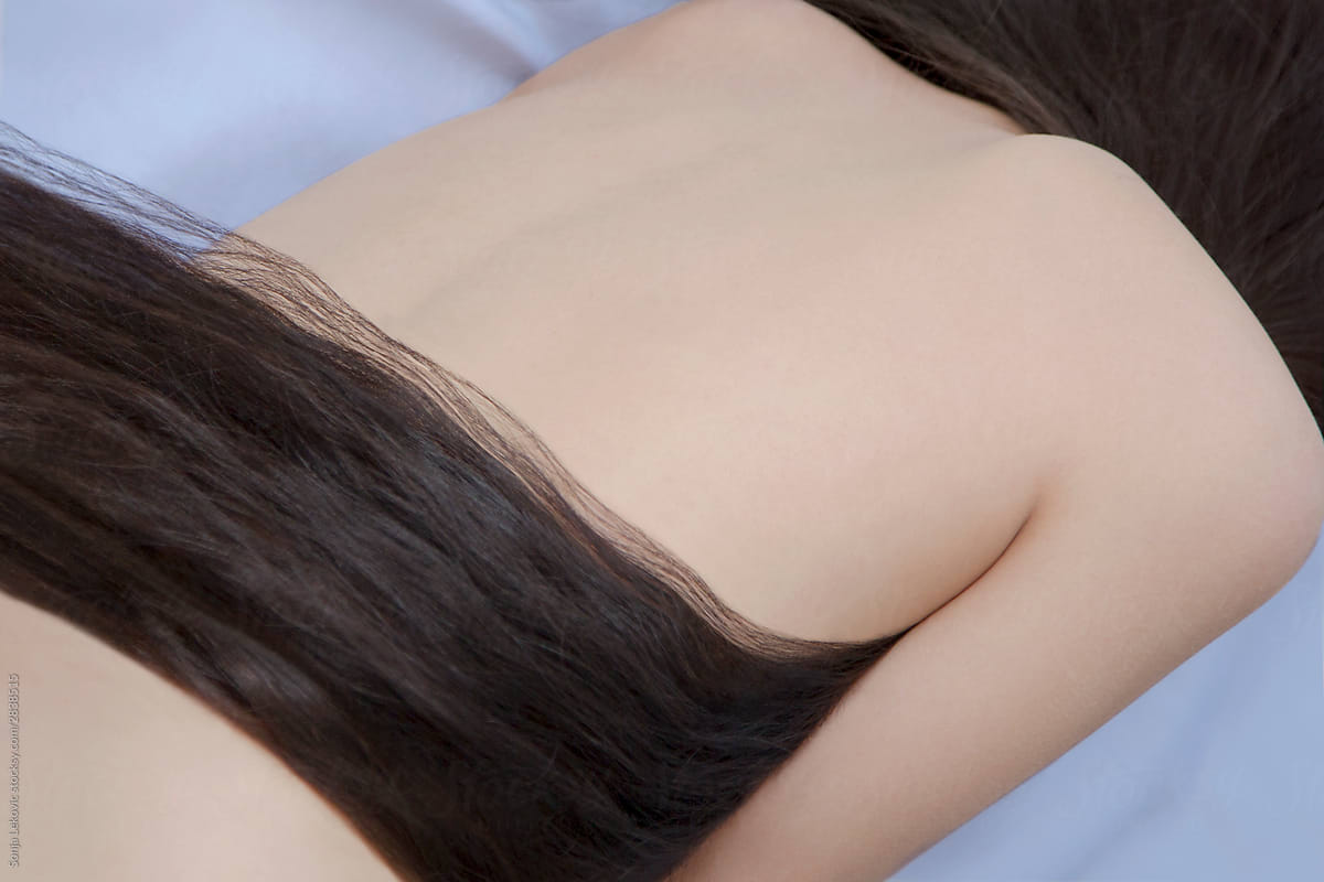 woman with long black hair from the back in bed