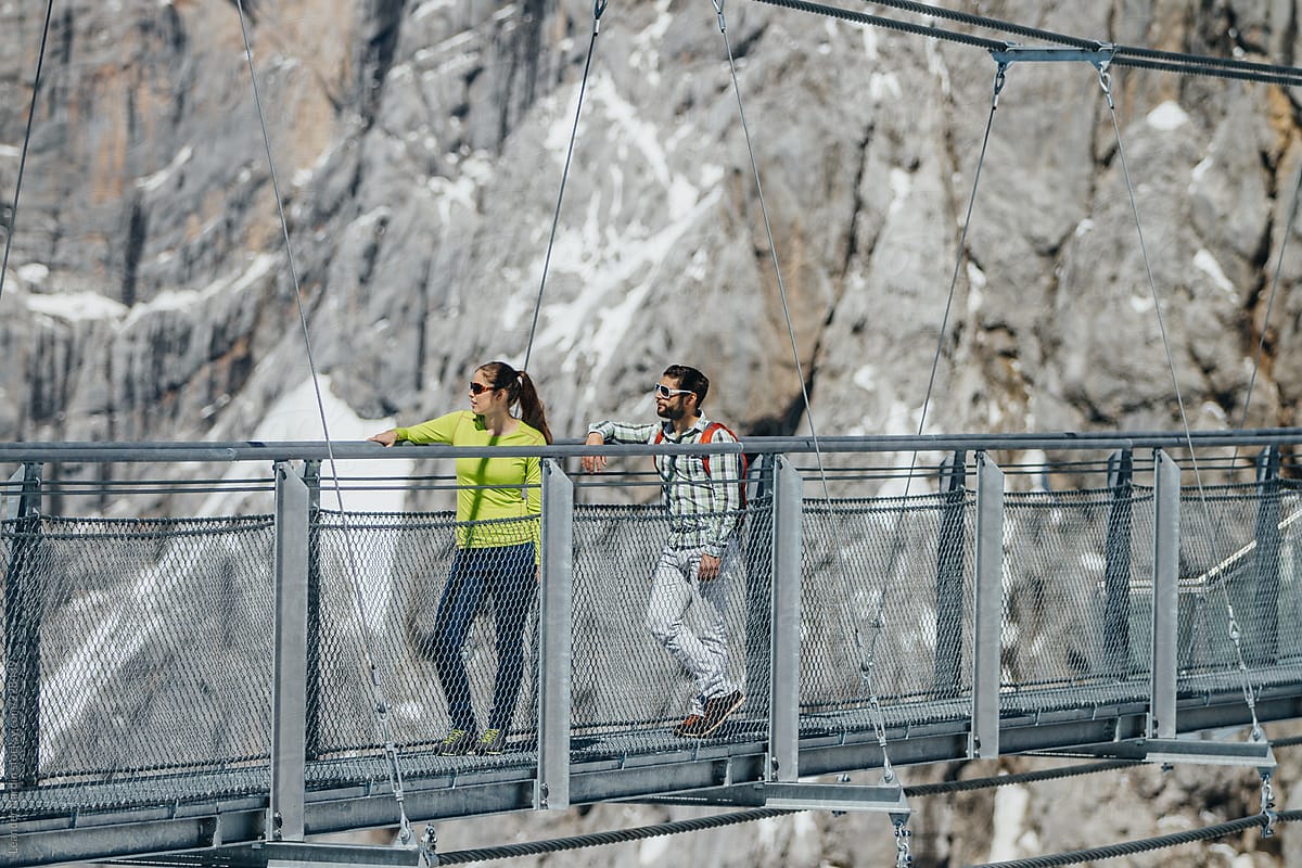 young casual couple leaning on a hanging bridge in the austrian alps enjoying the view