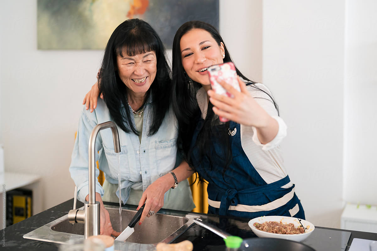 Content Japanese women taking selfie in kitchen at home