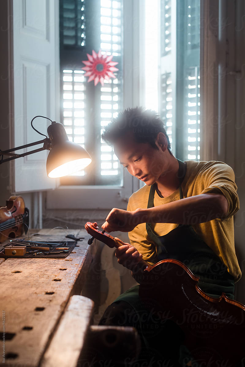 Intimate portrait of violin luthier repairing an instrument