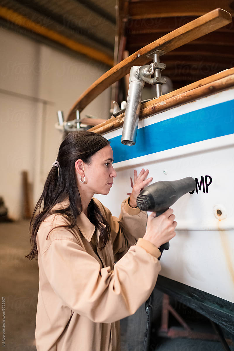 Focused woman working on boat restoration