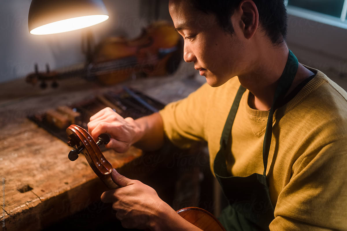 Intimate portrait of luthier working on violin