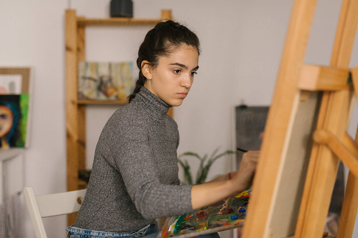 Young female artist painting in art studio