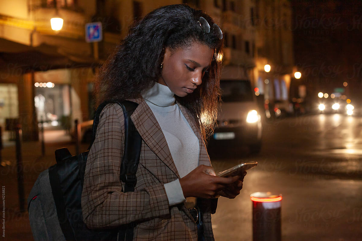 connected, young business woman using internet on smartphone at night