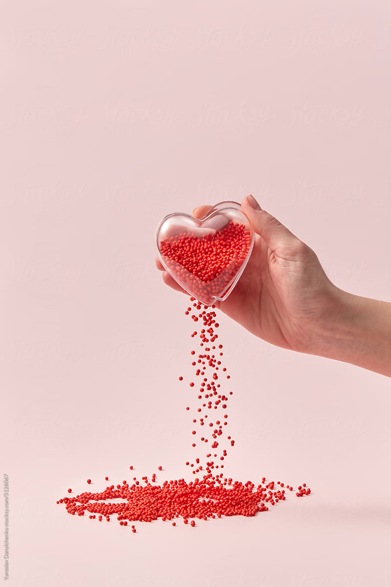 Glass heart in hand with red balls falling out.