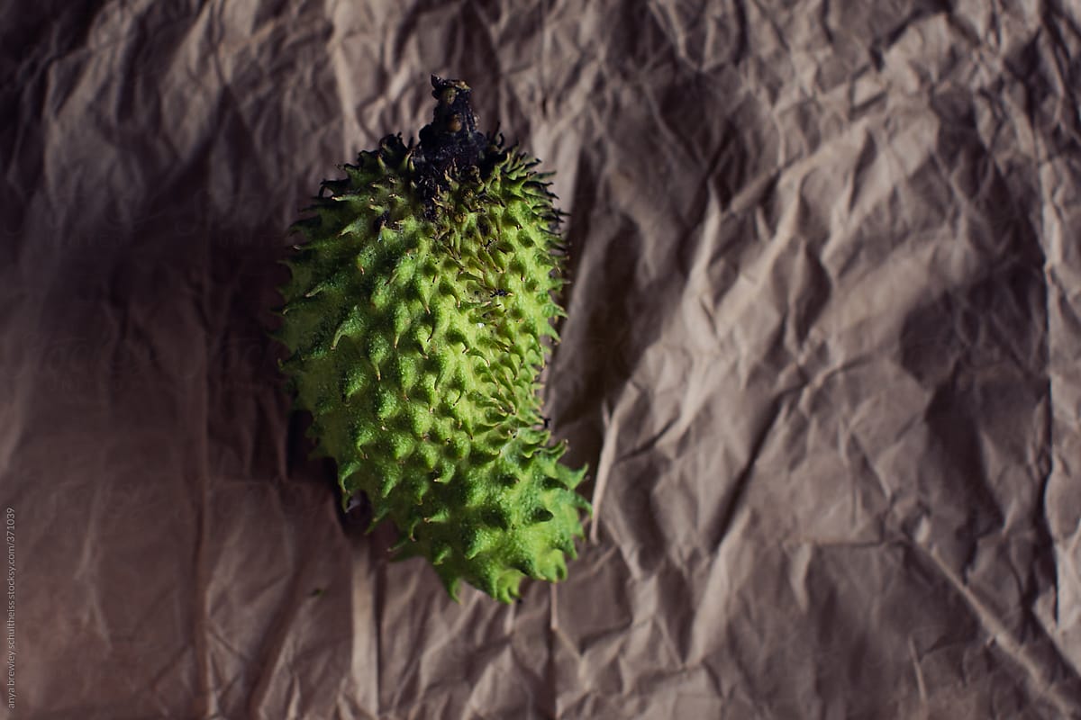 Spiny green soursop fruit on a brown paper background