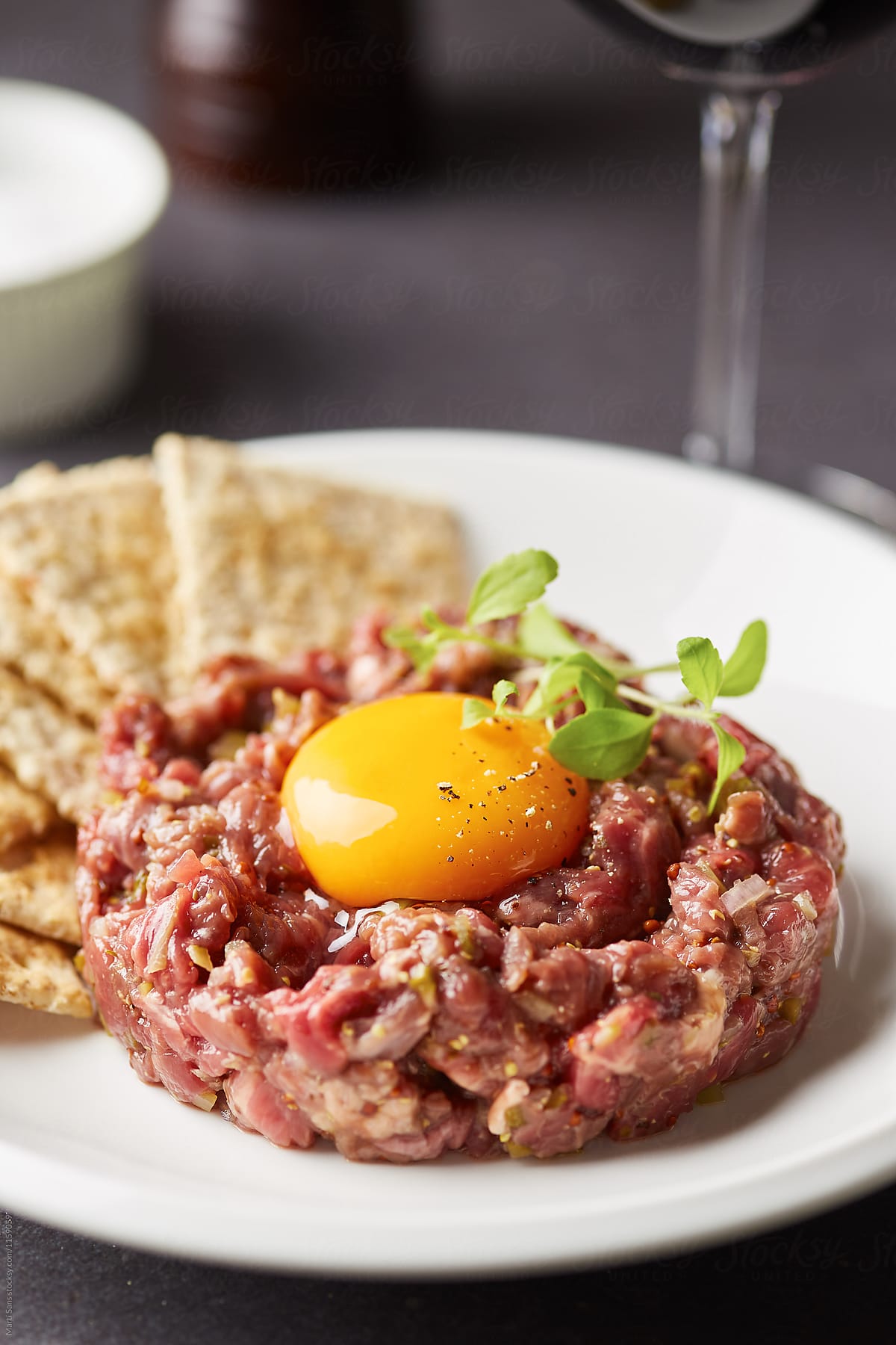 Homemade tartare with egg yolk on plate with crackers.