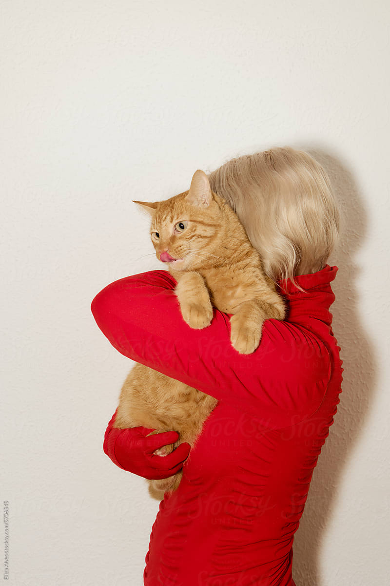 Woman wearing red and holding a orange cat