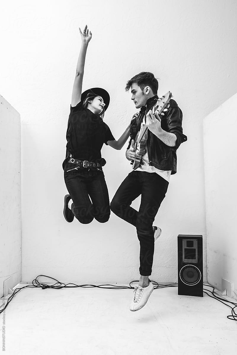 Rockers couple jumping with their electric guitar in recording studio.