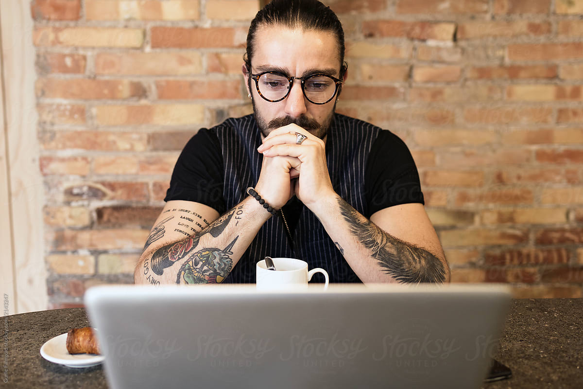 Handsome hipster in glasses working on laptop.