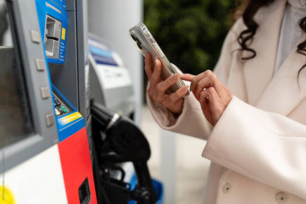 Woman Uses A Mobile App At The Petrol Station