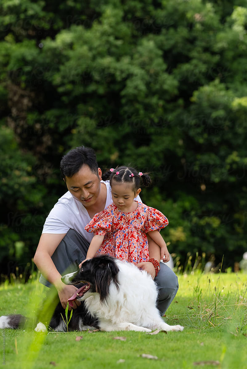 happy asian man with daughter and dog in the park