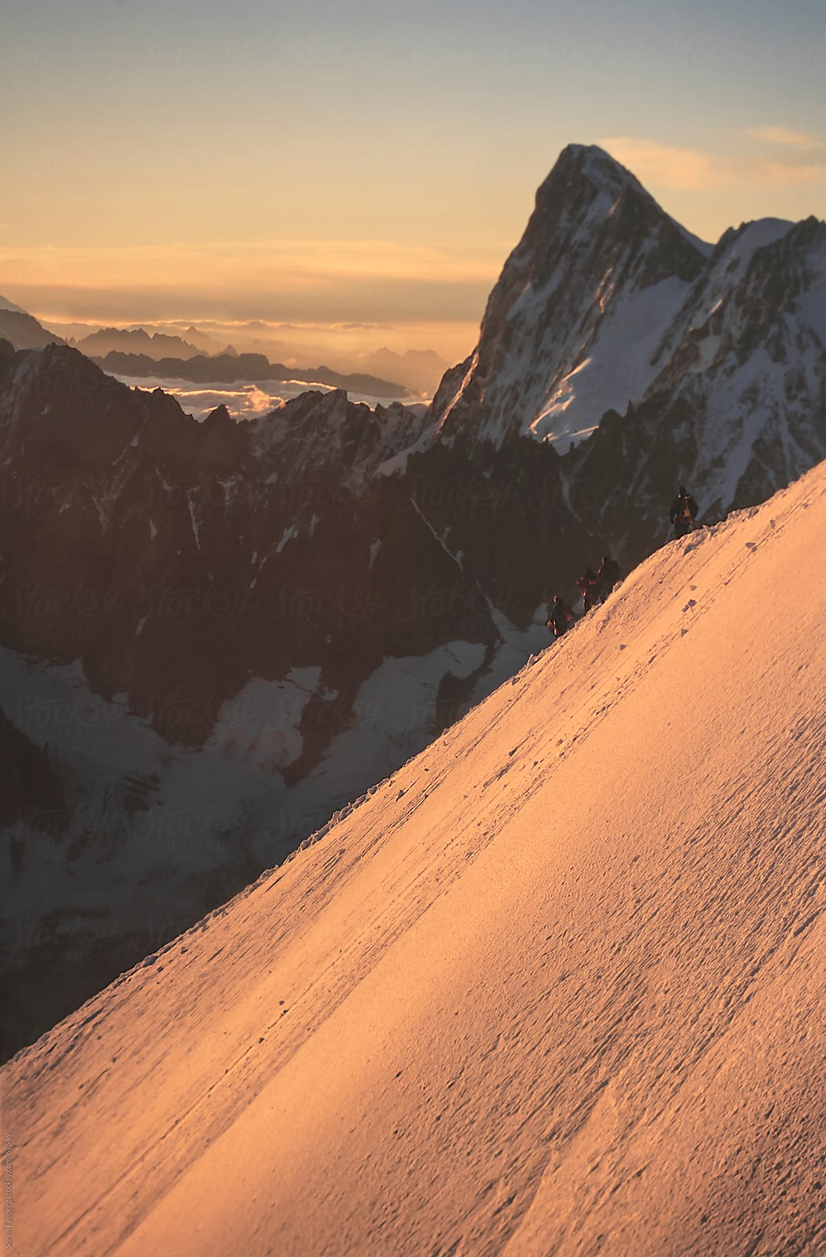 Mountain scenery with climbers descending snow ridge at sunrise