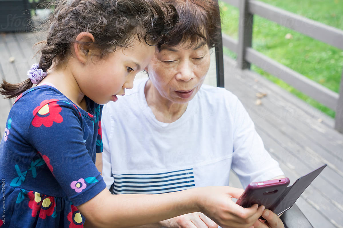 Asian lIttle girl, helping grandmother with mobile phone