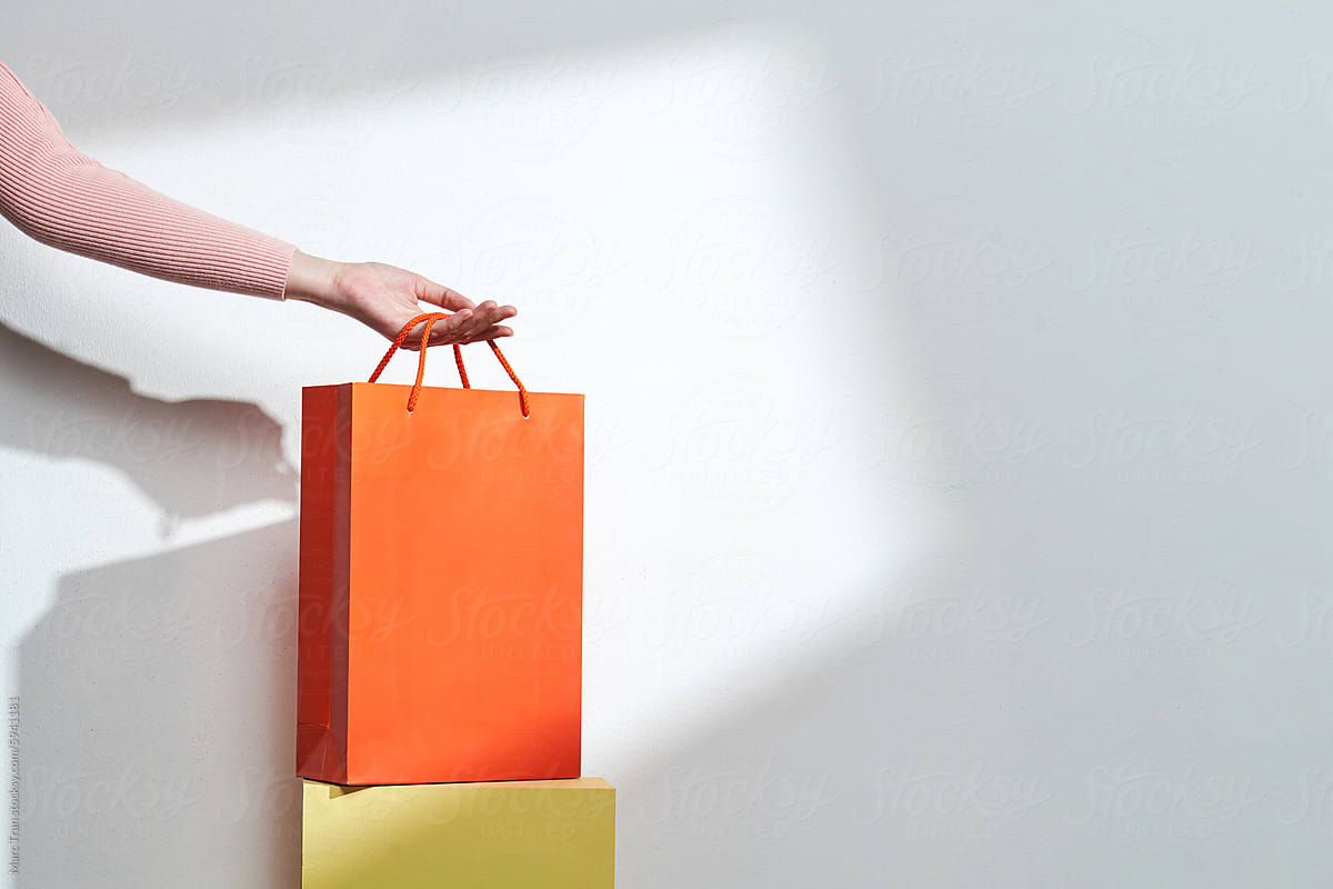 Hand-putting a bunch of shopping bags on colorful goods packaging