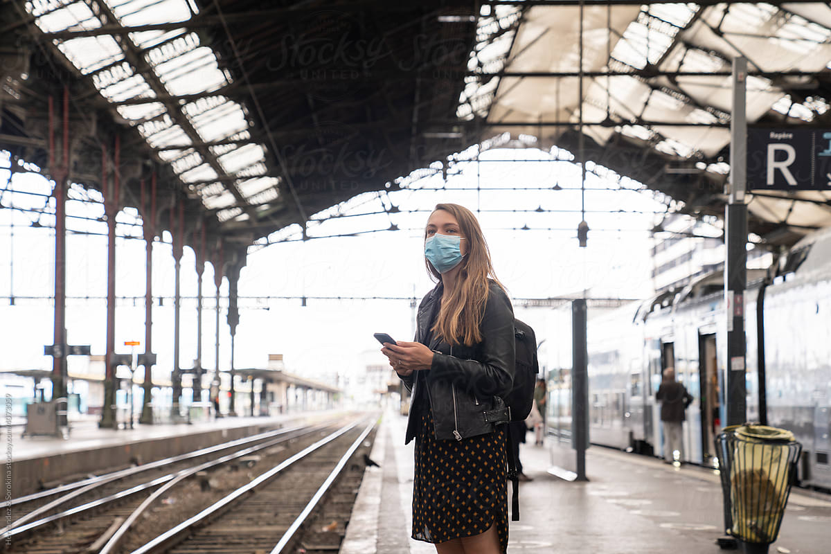 Wearing Medical Mask Holding Phone At Train Station