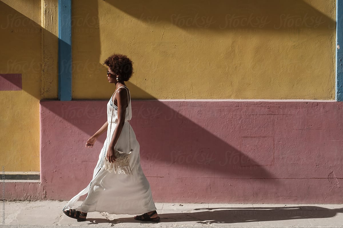 African Woman Wearing White Dress Walking Down The Street By Stocksy Contributor B Krokodil