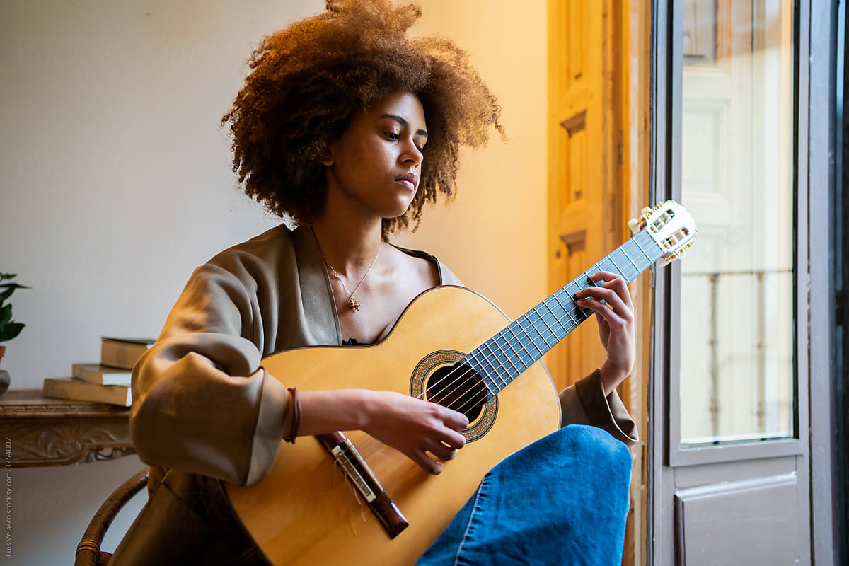 Black Woman With The Acoustic Guitar Next To The Window At Home.