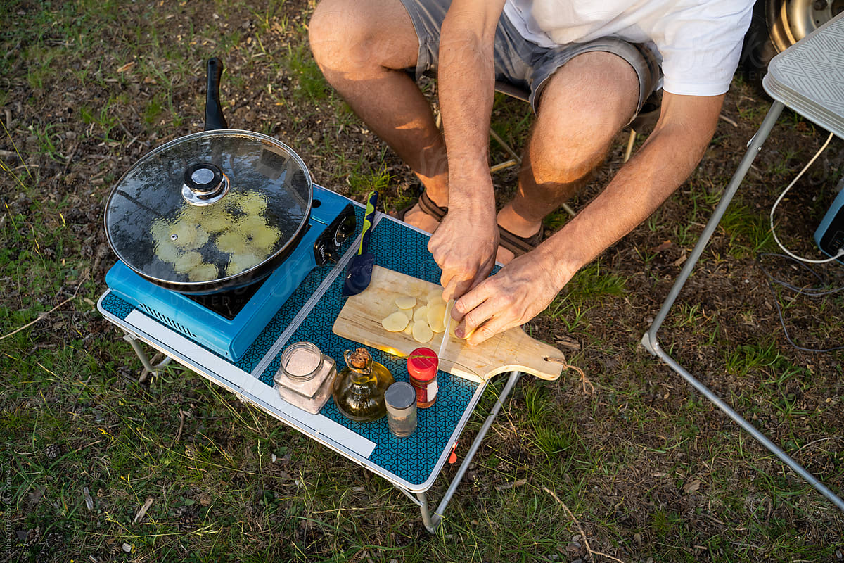 Man camping and cooking with camper van in nature