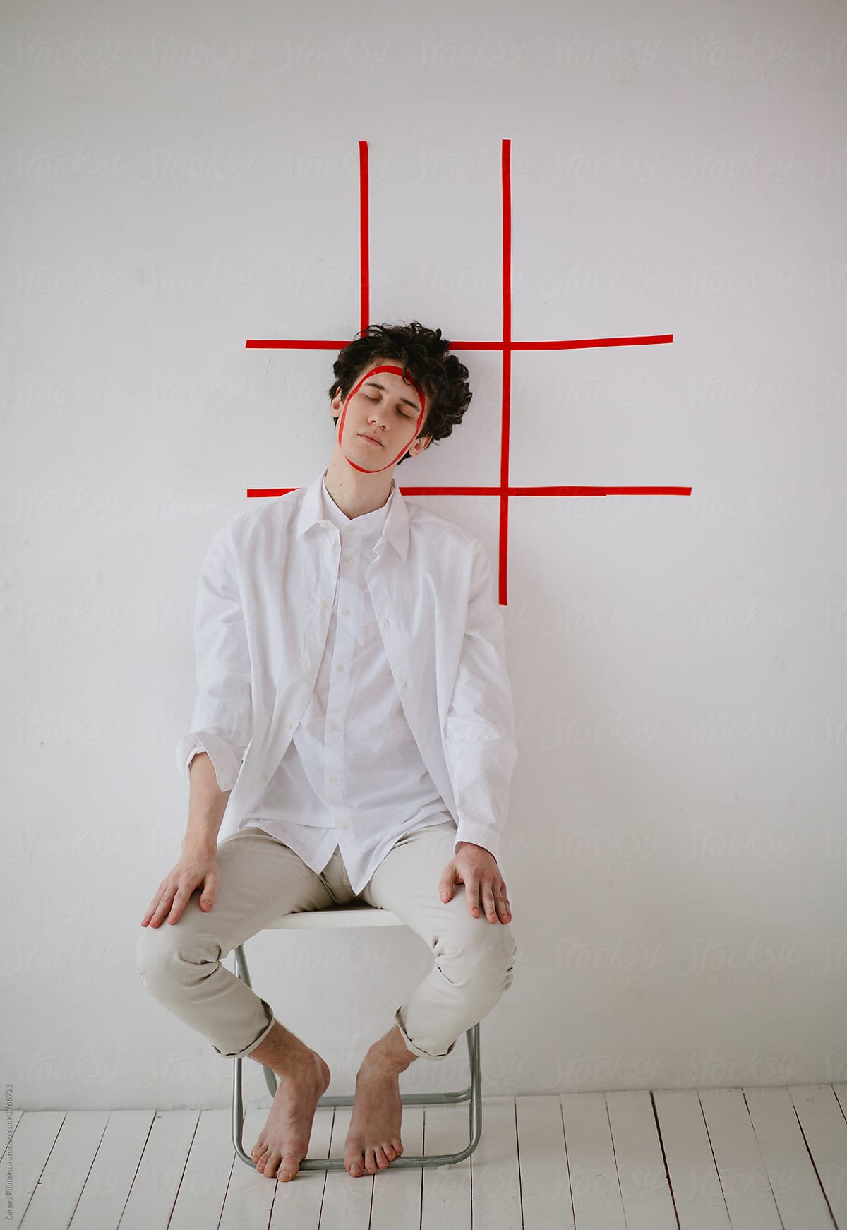 Young man posing with red sticky tape on his face