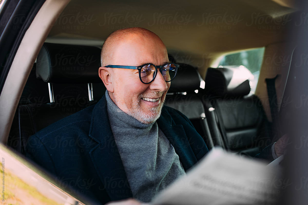 An Older Man Reading Newspapers in the Car
