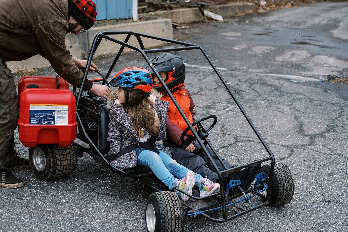 Father filling up children\'s go kart with gasoline from a tank