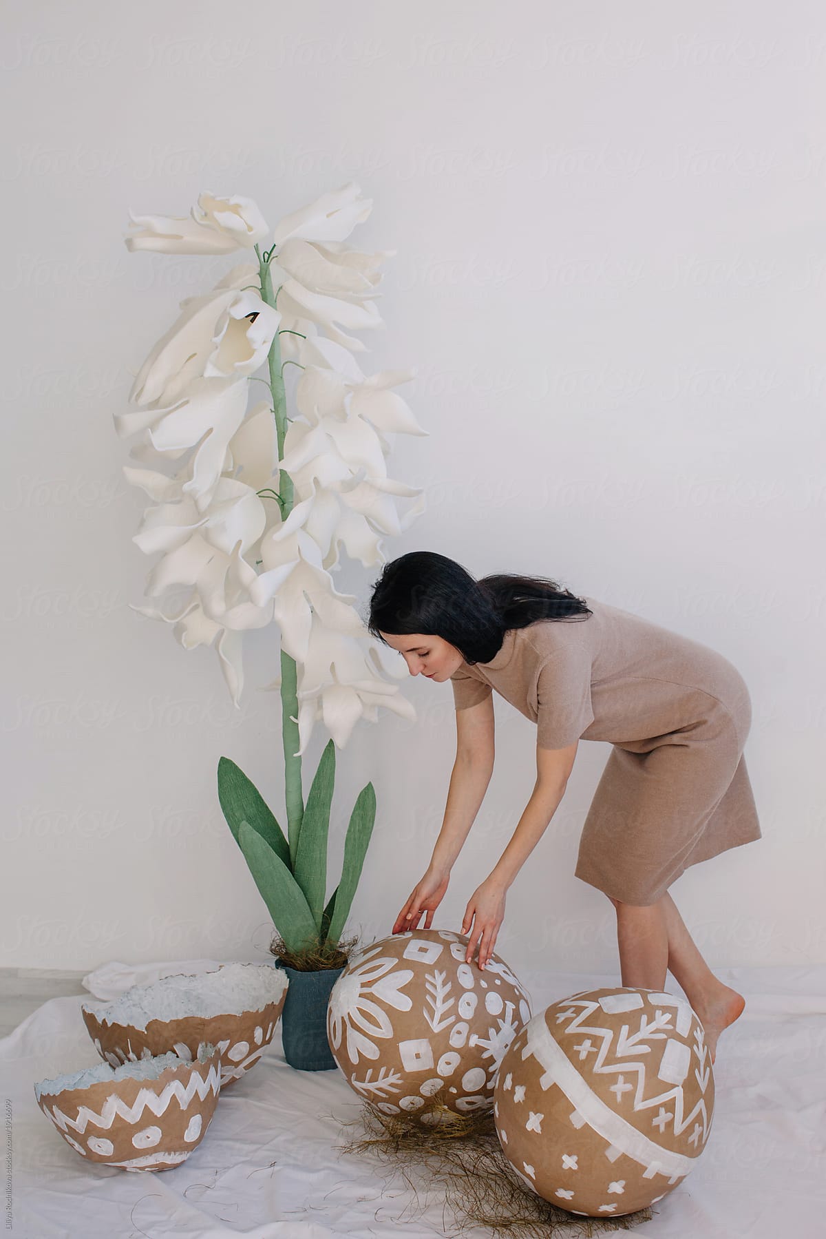 Lovely young woman arranging Easter decor with giant painted eggs and white hyacinth
