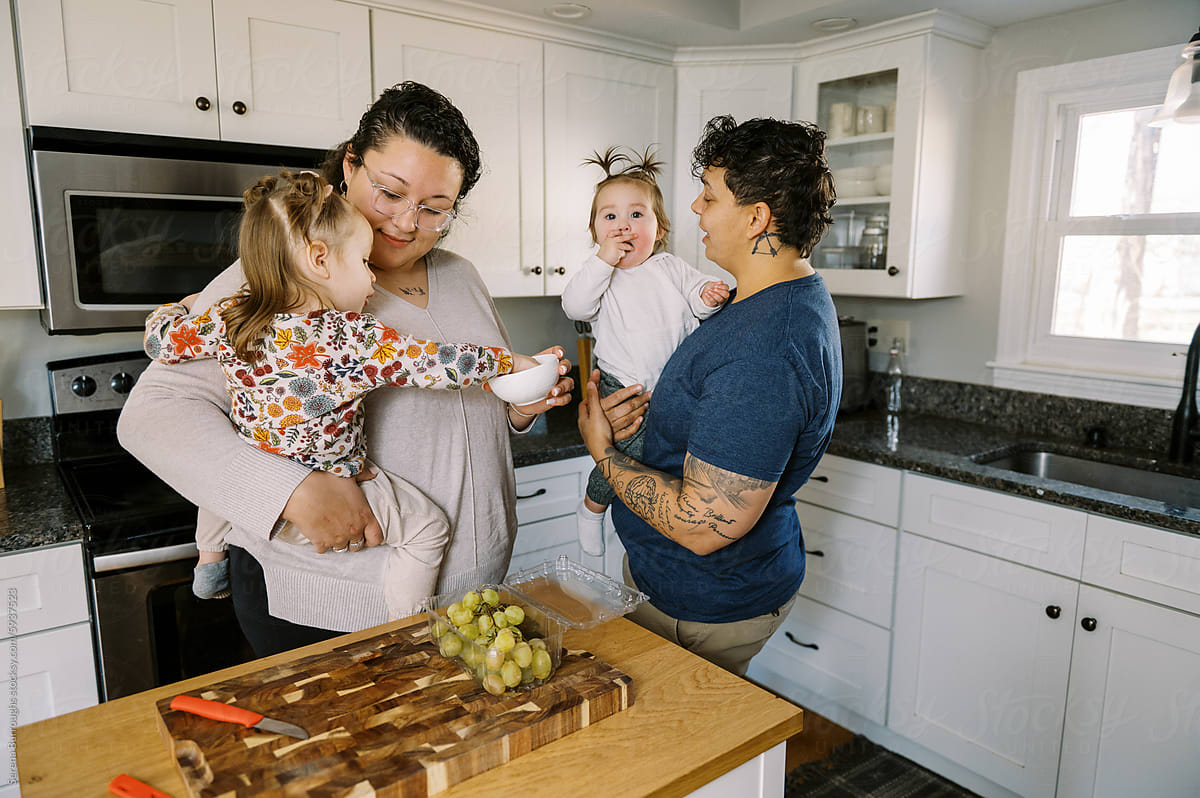 LGBTQ Family with children standing in kitchen and having a snack