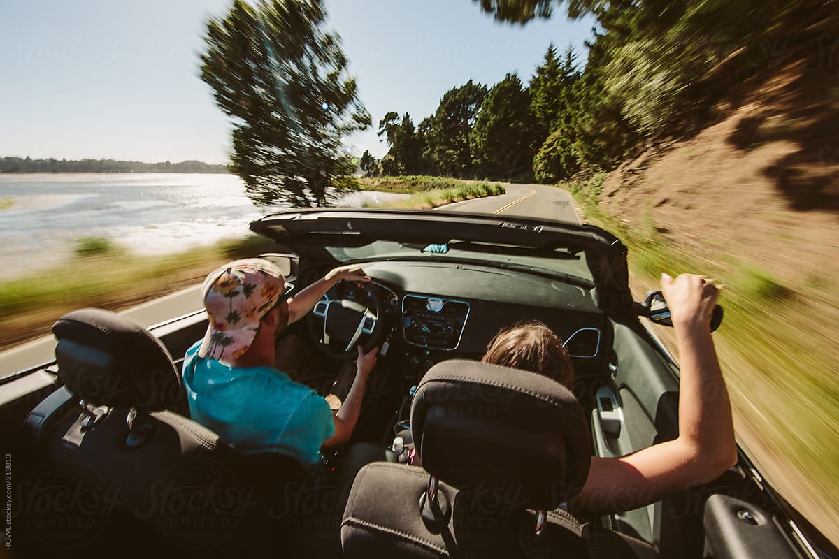 A Happy young couple driving highway 1 in California in their convertible