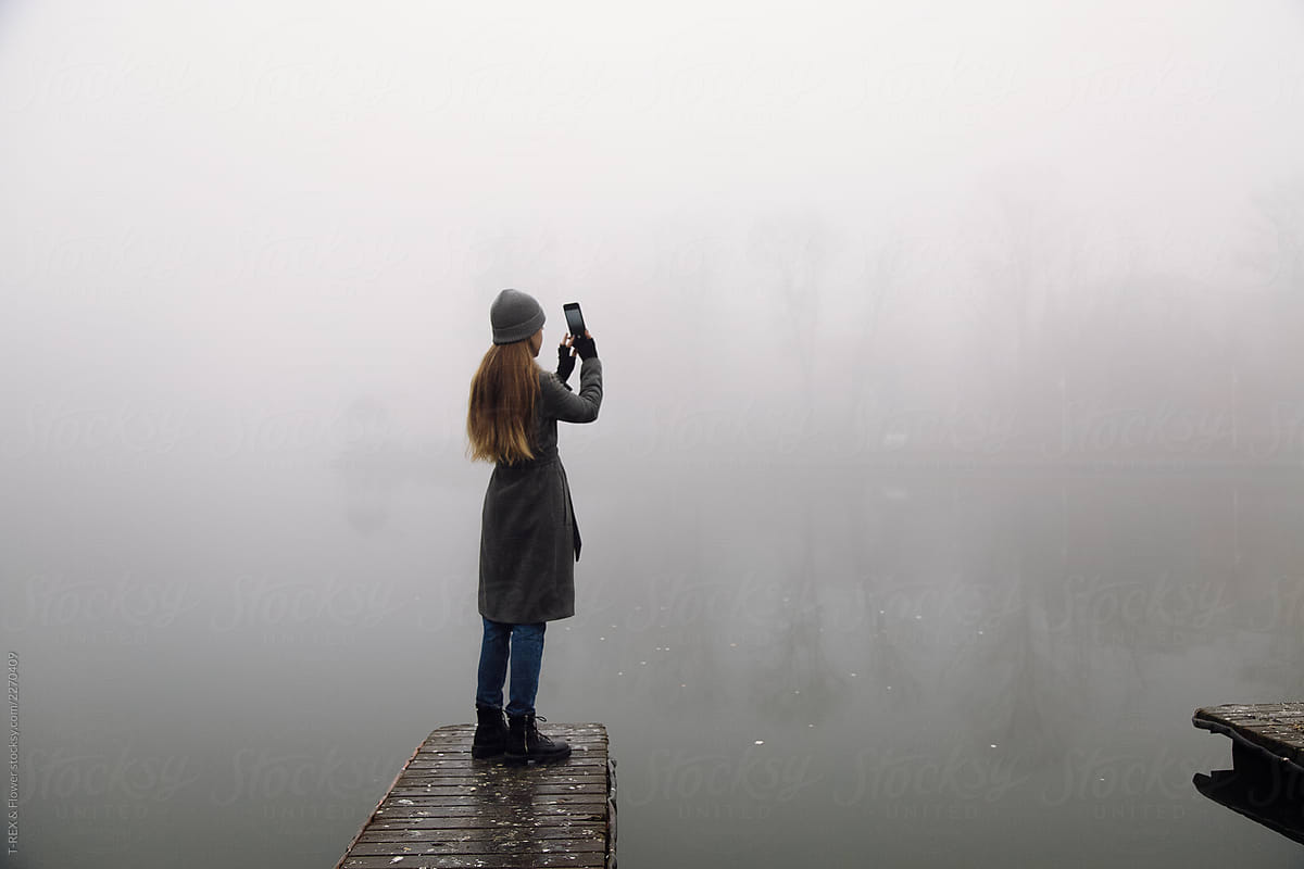 Unrecognizable woman taking pictures on foggy day