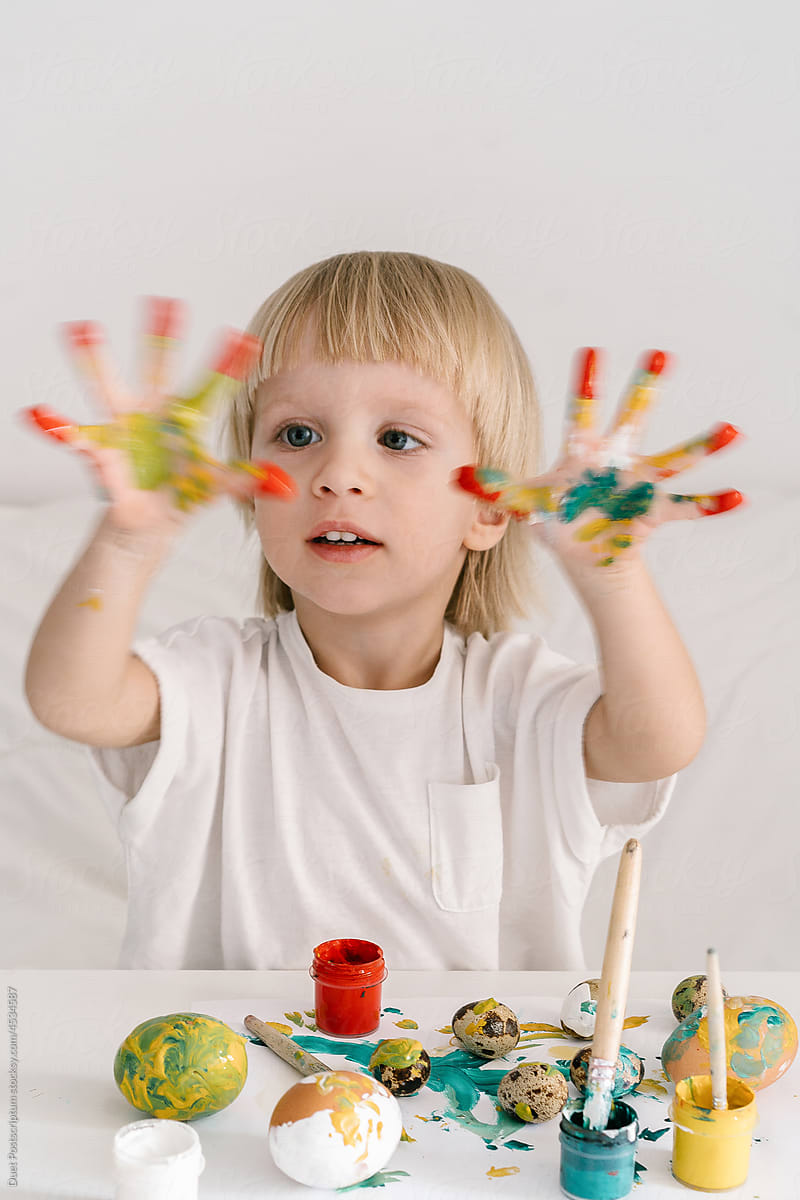 Boy in the process of coloring eggs stained his hands in paint