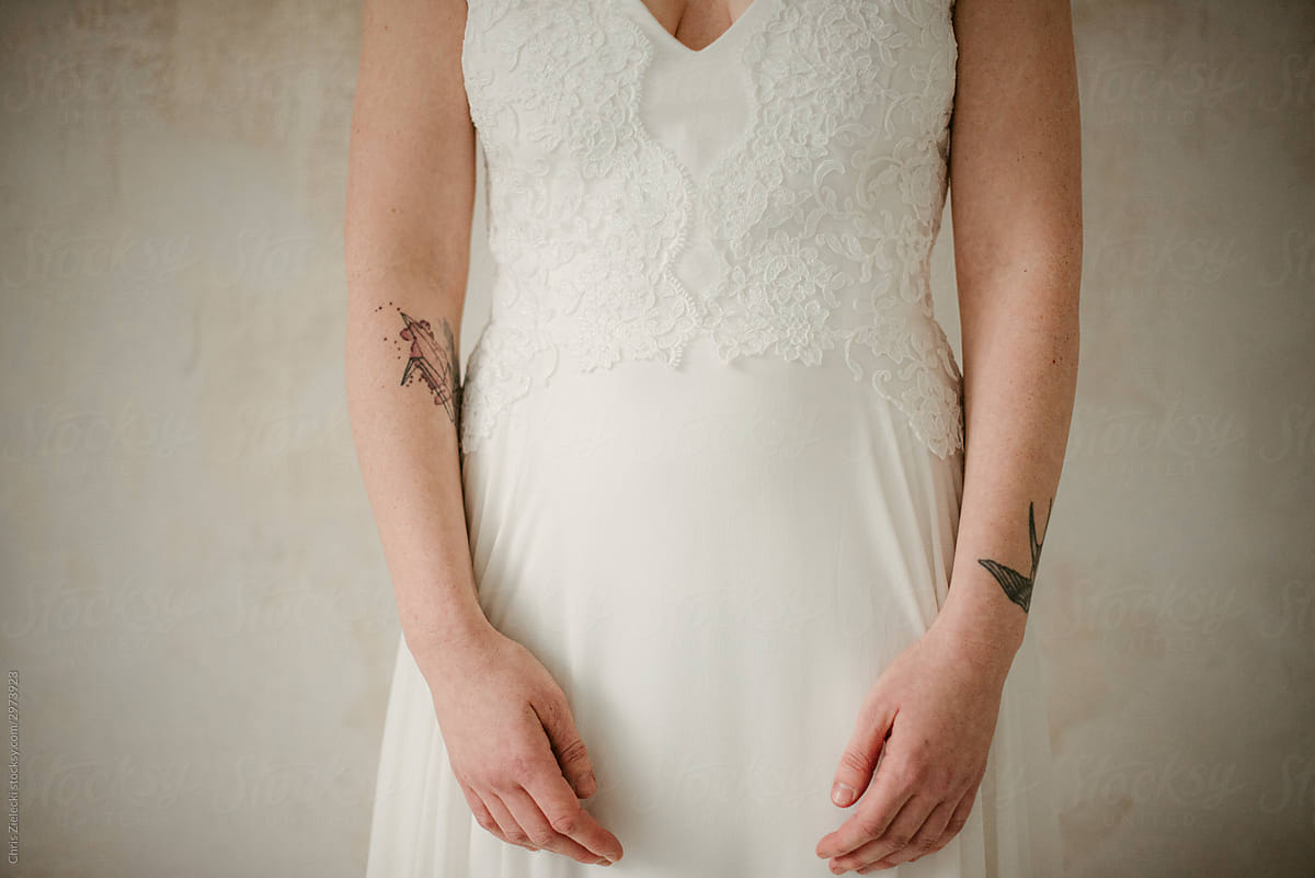 Faceless tattooed bride in trendy white gown