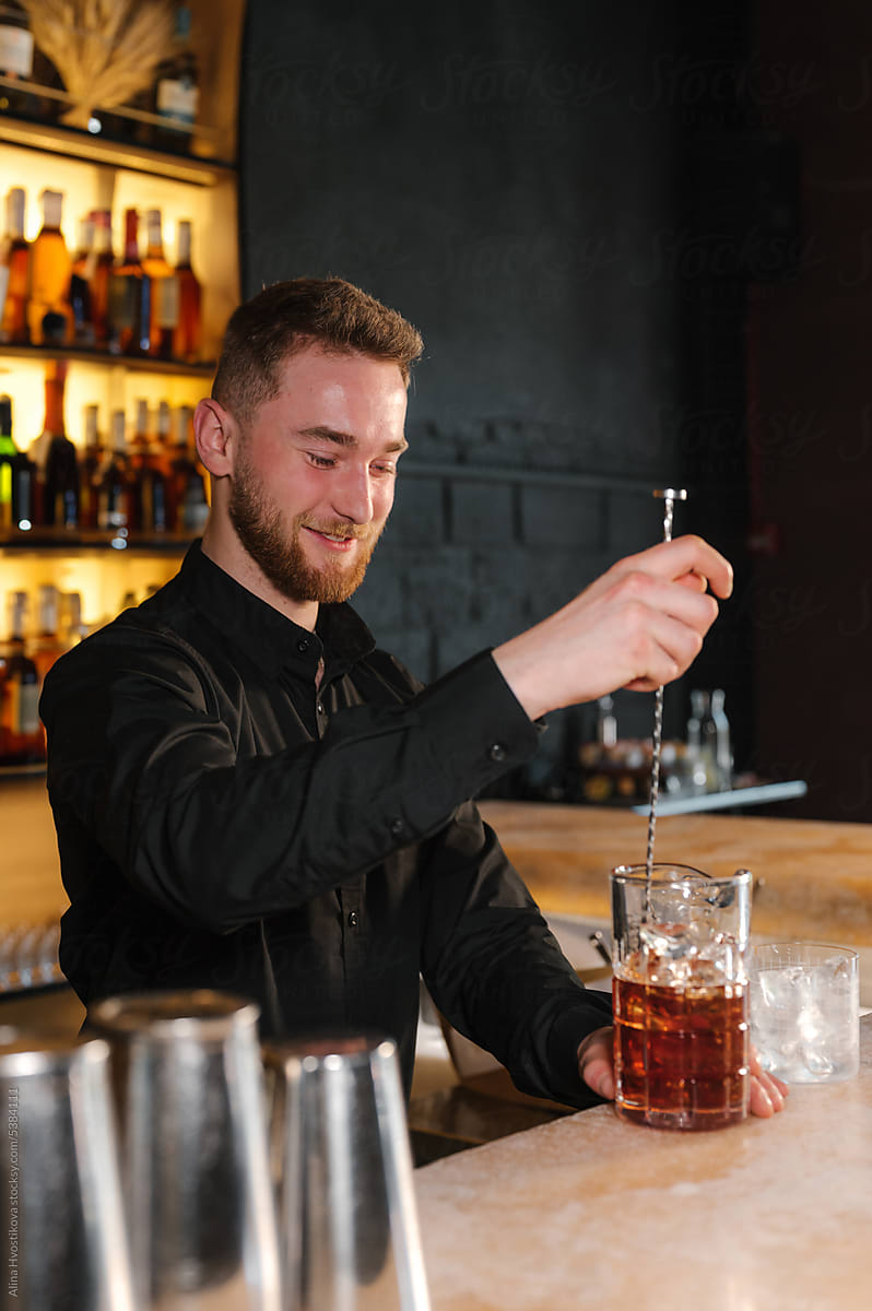 Happy barman mixing Negroni cocktail with spoon