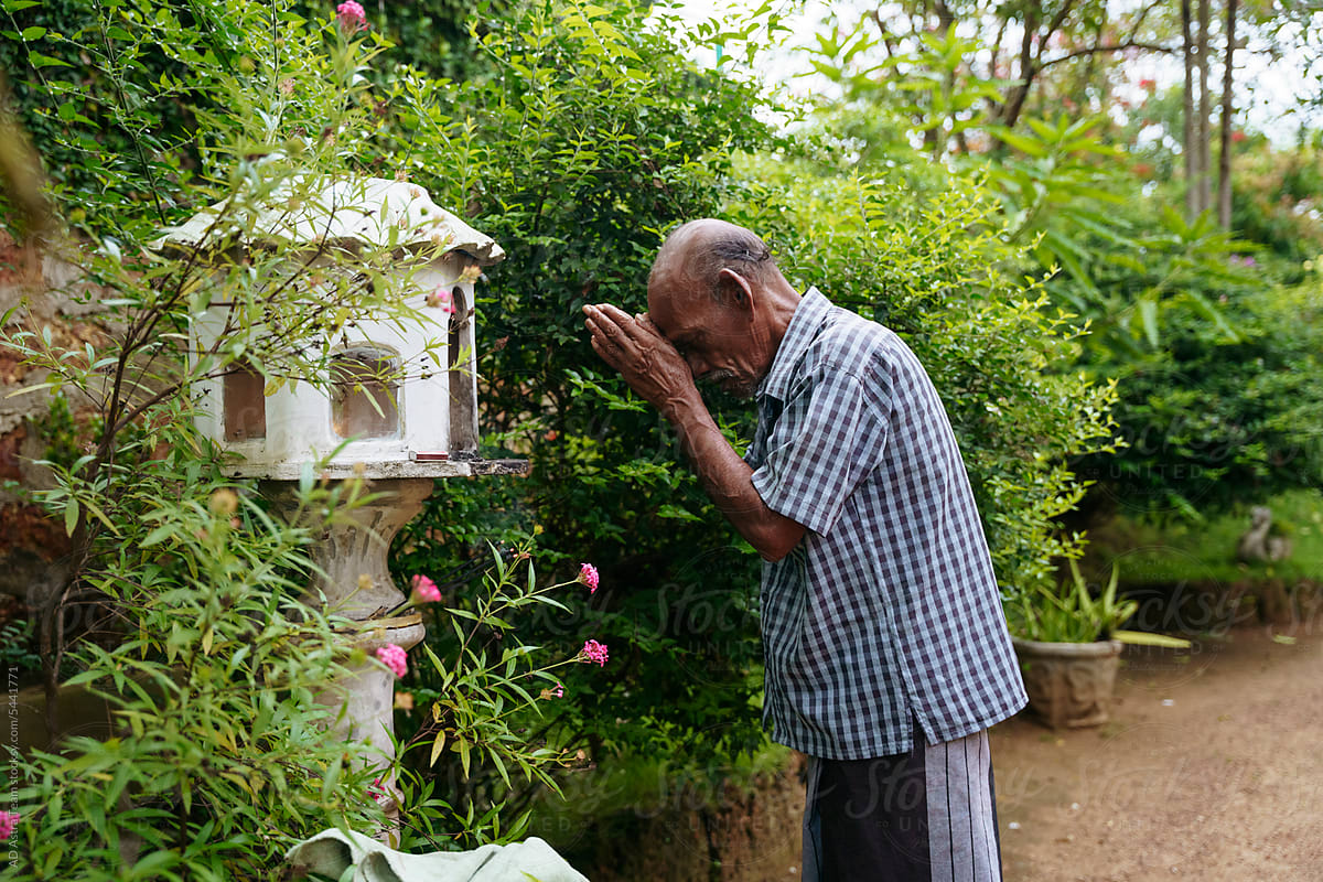 An elderly Buddhist prays in front of the altar
