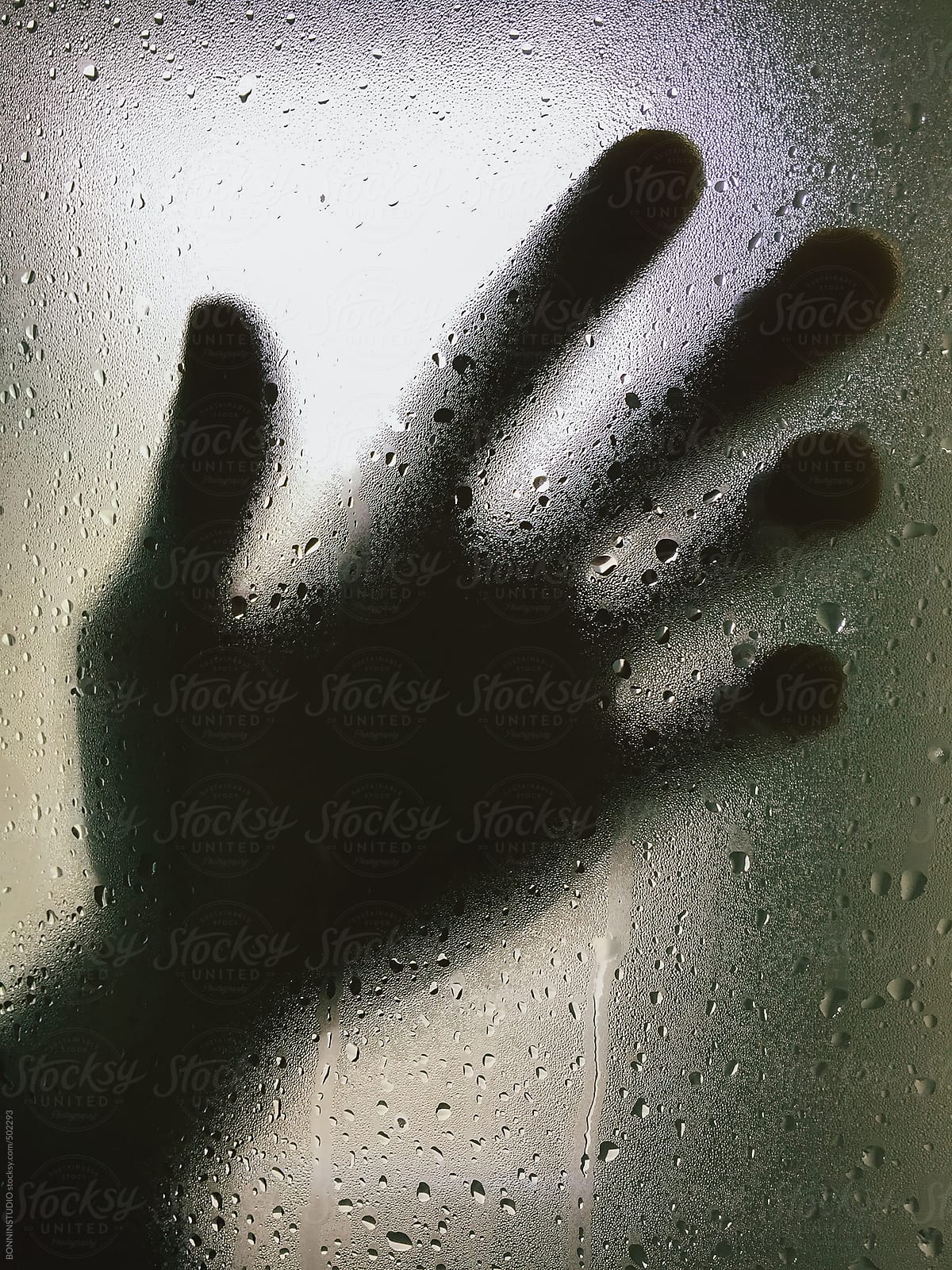 Hand on a wet glass inside a shower.