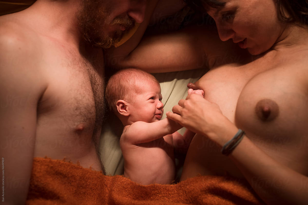 Angry baby on bed with mother and father