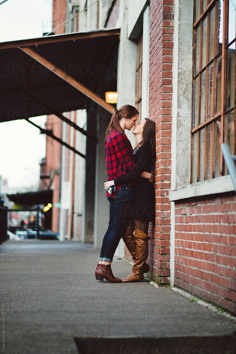Lesbian Couple Embrace Against Brick Wall During A Date Downtown By Stocksy Contributor Kate