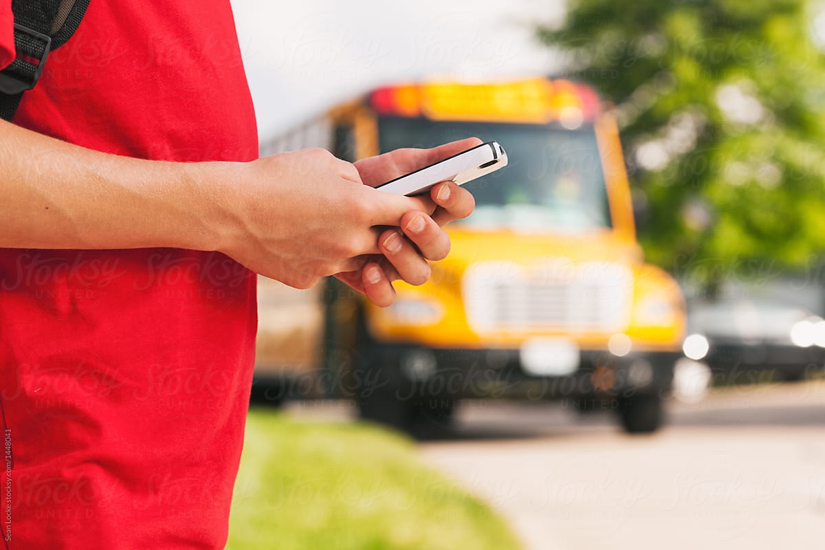 School Bus: Boy Uses Cell Phone While Waiting For Bus