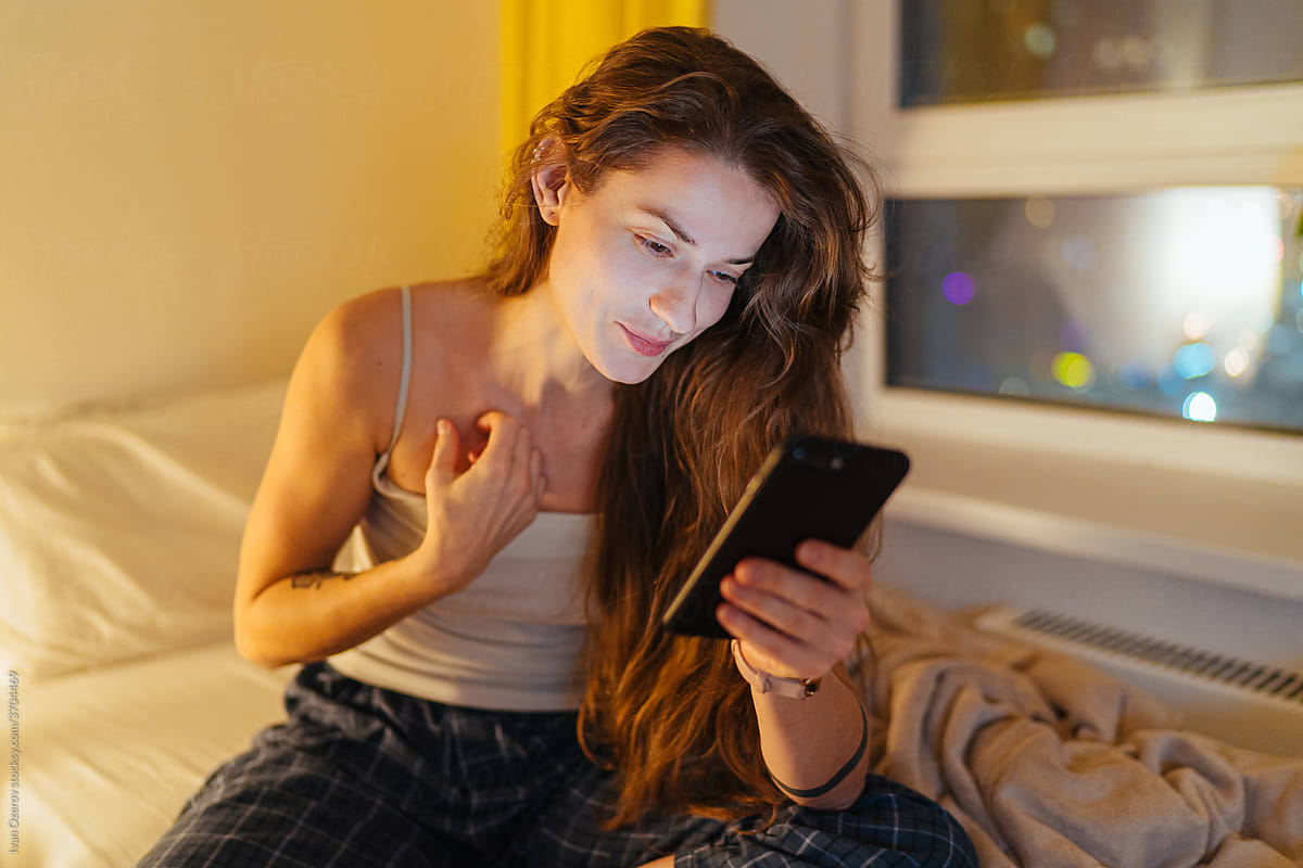 Young woman using smartphone in bedroom